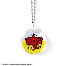 Load image into Gallery viewer, Keith Haring art with red flying devil printed on round clear acrylic pendant filled with yellow liquid v