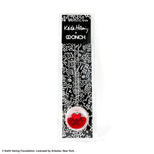 Load image into Gallery viewer, Keith Haring art with three men holding up red heart printed on round clear acrylic pendant filled with red liquid inside a black and white all over print by Kieth haring packaging with collaboration logo with designer ONCH
